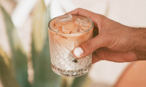 A close-up view of a resident's hand holding a glass with a foamy drink at Vestara 72 in Papillion, Nebraska