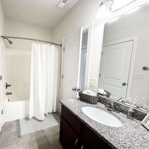 Bright bathroom with vanity, mirror, and soaking tub at South Fork Village in Belmont, North Carolina