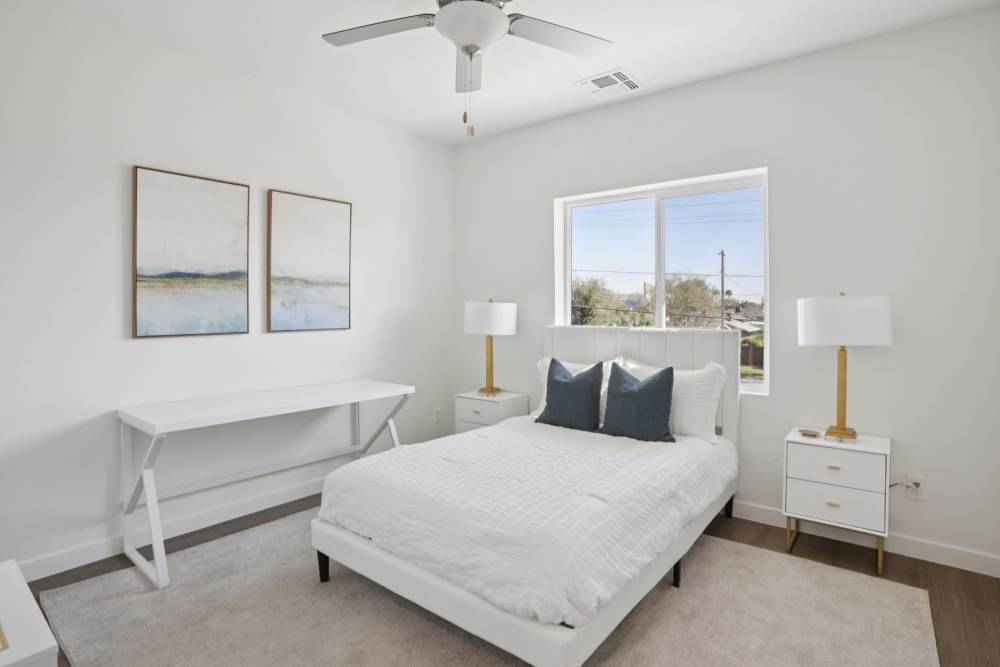 A bedroom with a bed, nightstands, and a window.