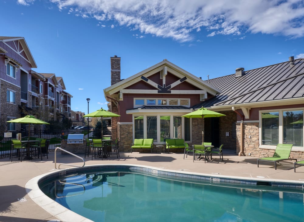 Lounge chairs, tables, and umbrellas around the pool at M2 Apartments in Denver, Colorado