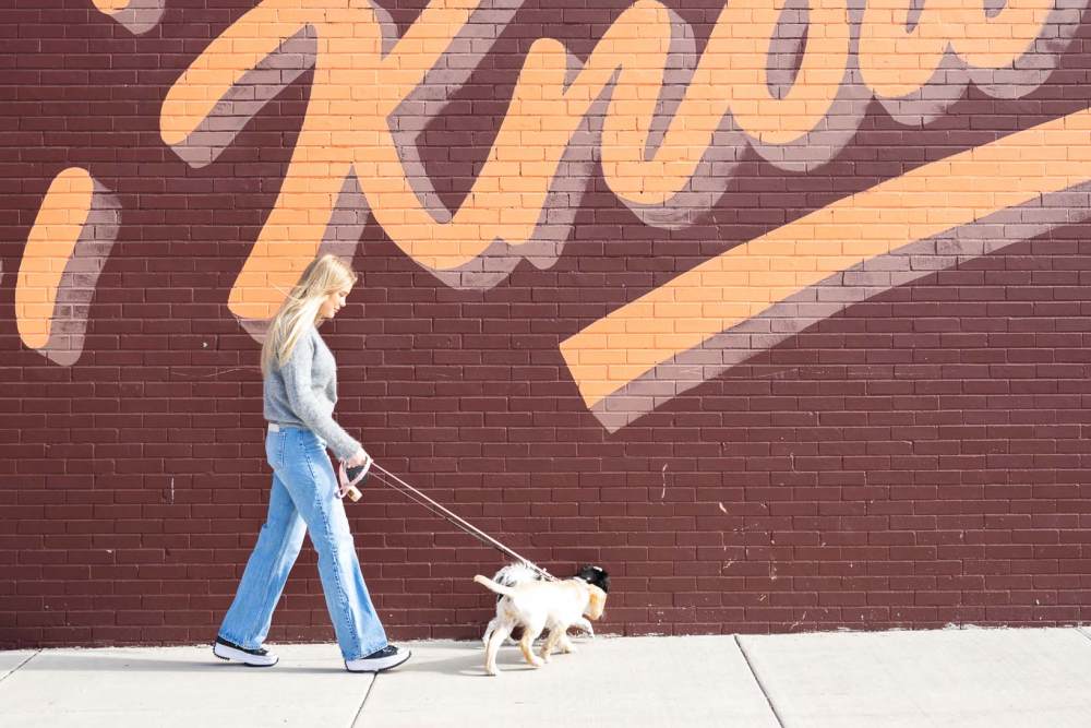 Resident walking her dog past a mural near The Scottie in Nashville, Tennessee