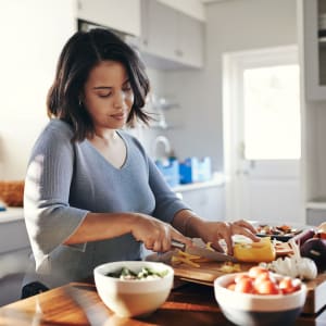 Resident preparing a meal in her fully equipped kitchen at Highlands of Grand Prairie in Grand Prairie, Texas