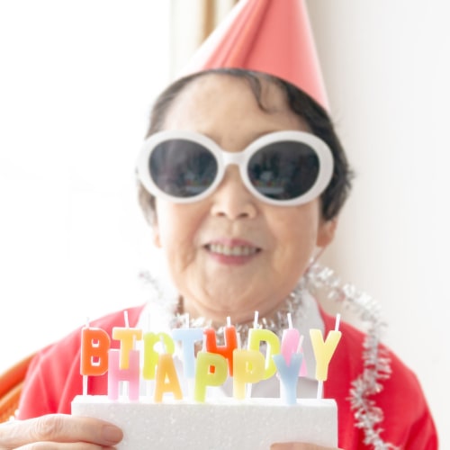 Senior woman celebrating a birthday with cake, candles, and a party hat at Oxford Vista Wichita in Wichita, Kansas