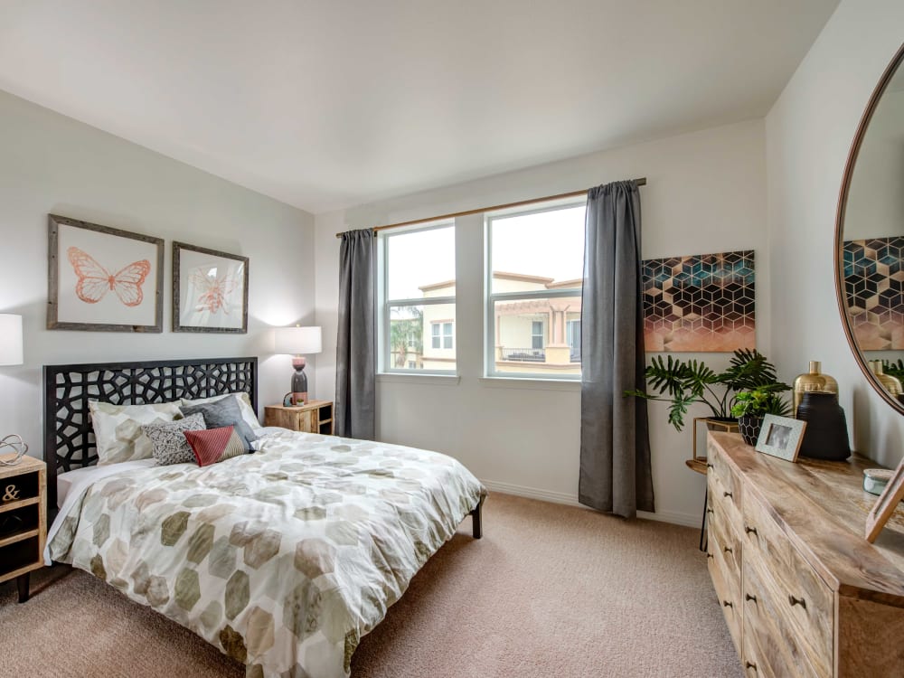 Beautifully decorated bedroom with plush carpeting and draped windows in a model home at Sofi at Topanga Canyon in Chatsworth, California