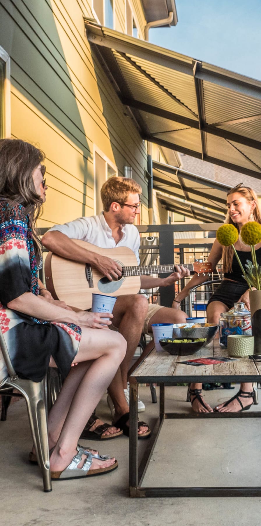 Resident playing guitar for friends on a private patio at The Thompson in San Marcos, Texas