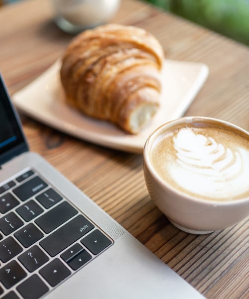 Coffee and croissant next to a laptop at Allegheny Branch House Lofts in Pittsburgh, Pennsylvania