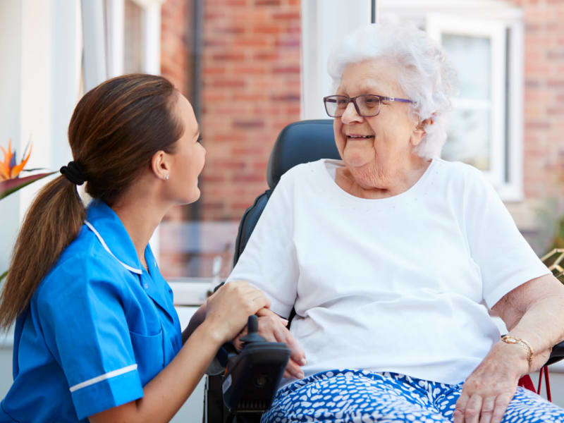 Caretaker sitting and conversing with a resident in hospice care at Geneva Lake Manor in Lake Geneva, Wisconsin