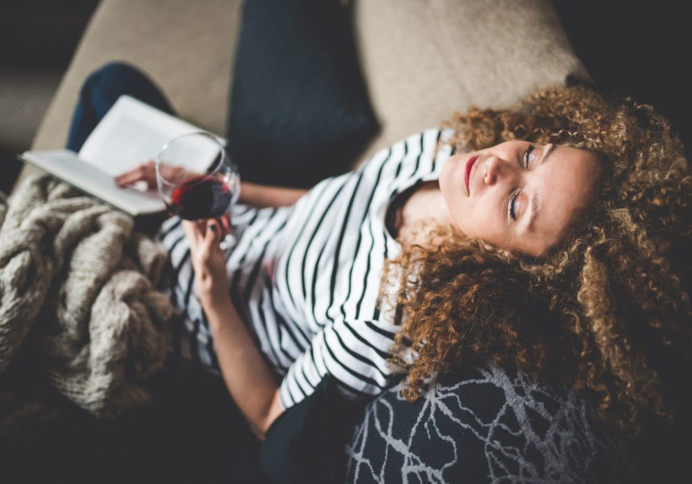 Resident relaxing on her couch enjoying some wine at Pine Crest Apartments in Milford, New Jersey