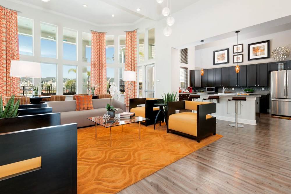 Community lounge with orange area rug and comfy seating at Art Avenue Apartment Homes in Orlando, Florida