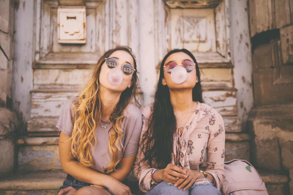 Two friends hanging out blowing bubbles with their gum near Highlands at Alexander Pointe in Charlotte, North Carolina