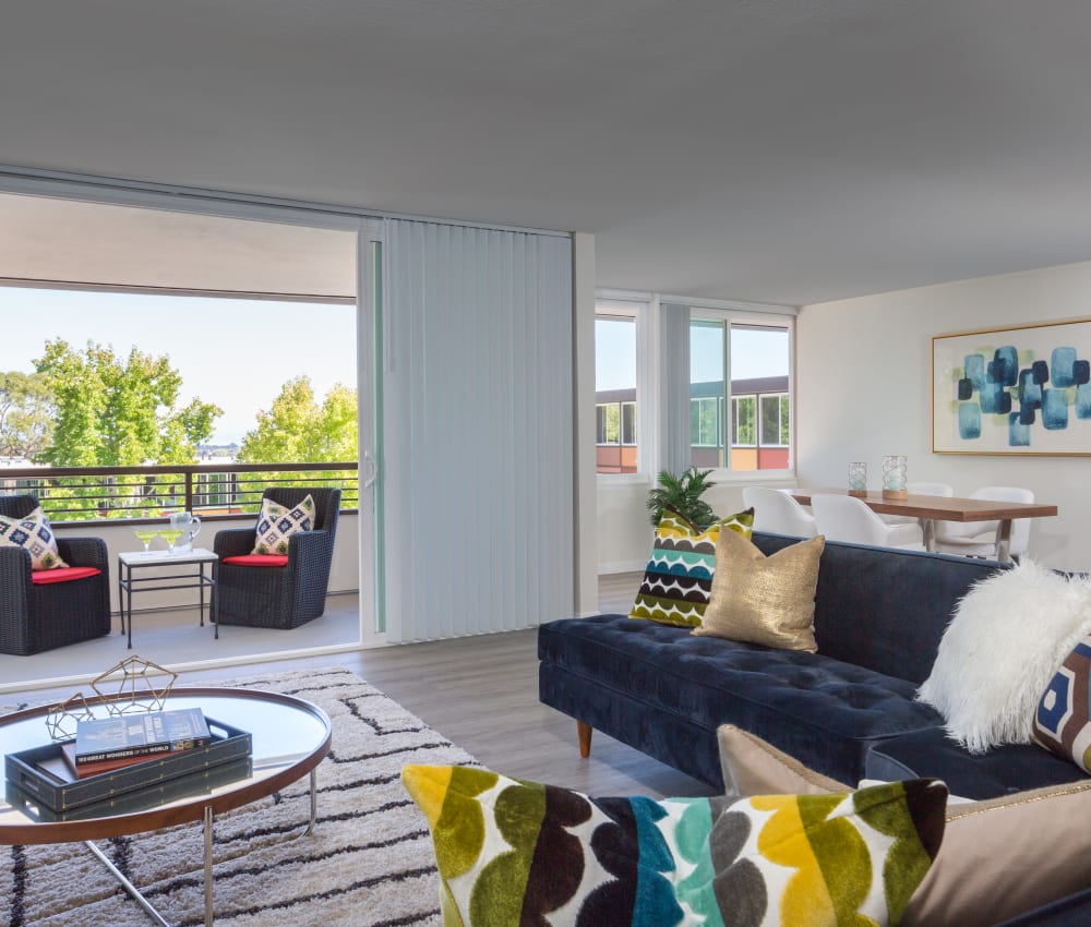 Spacious living area looking out onto the well-decorated private balcony outside a model home at Sofi Belmont Glen in Belmont, California