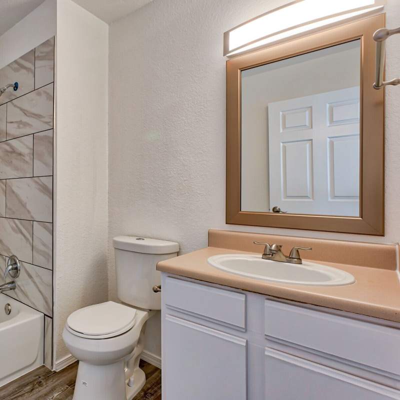 Bathroom with mirror, tub and storage space at The Gardens At Duncan Apartments in Duncan, Oklahoma