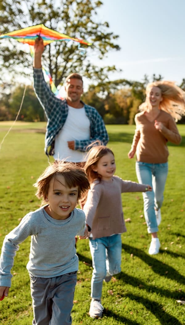 Happy family playing in the park nearby a Ray Stone Inc. community