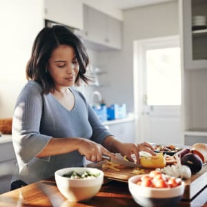 Resident chopping vegetables in her fully-equipped kitchen at Stonegate Apartments in Mckinney, Texas