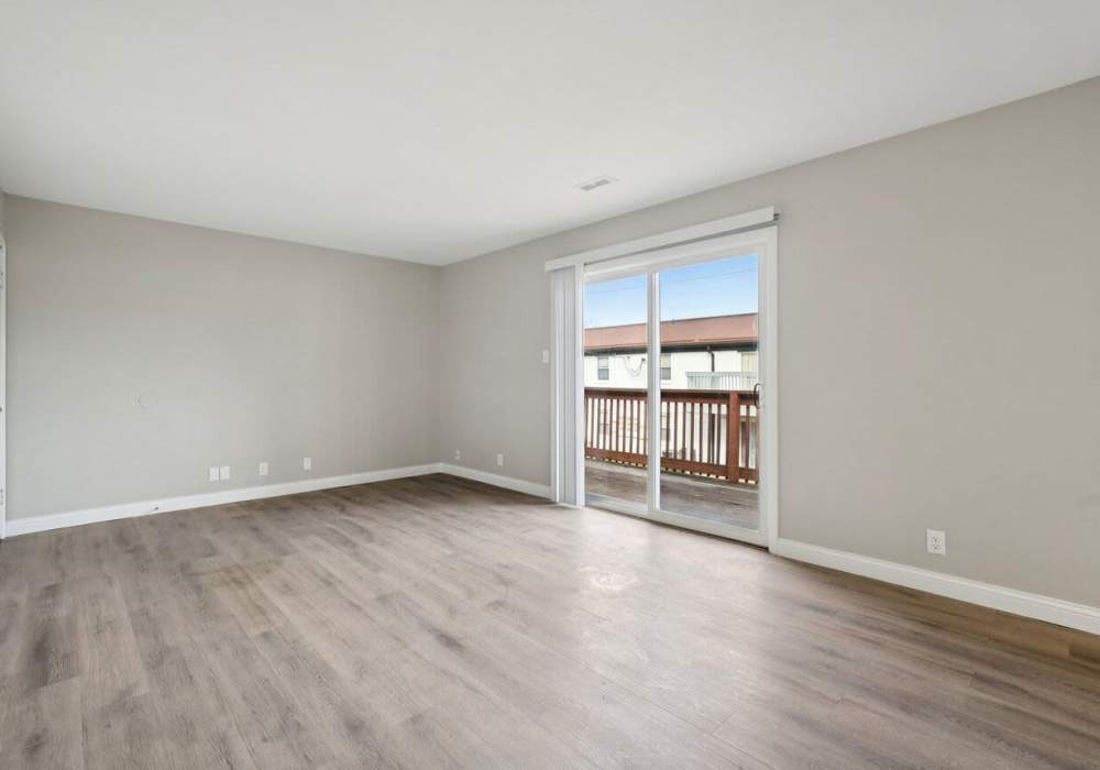 Unfurnished living room with wooden flooring and access to private patio at Charleston Square Apartments in Columbus, Indiana