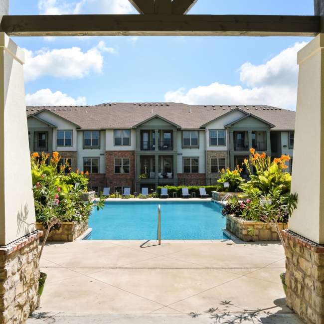 View of a swimming pool thru pillars at Boulders at Overland Park Apartments in Overland Park, Kansas