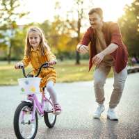 Resident helping his kid to learn bicycle at Village at Carlsbad in Carlsbad, New Mexico