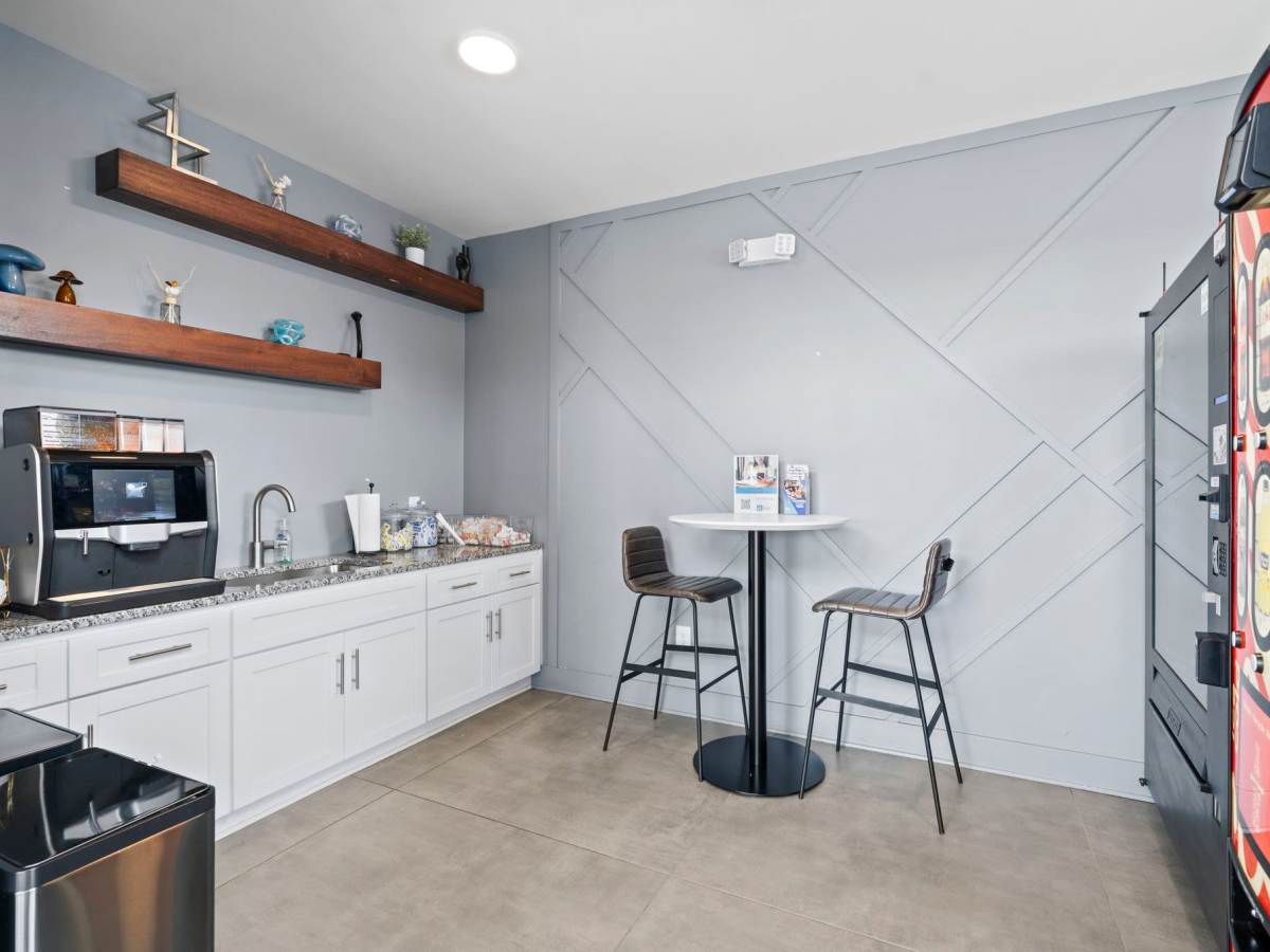 Community cafe with coffee machine, round table and barstool at The Rise at Regency in Henrico, Virginia