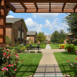 Pergola with flowers and walkway on the grounds of Parkway Villas in Grand Prairie, Texas