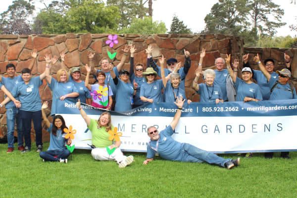 Staff and residents pose in front of a sign at Merrill Gardens at Santa Maria in Santa Maria, California. 