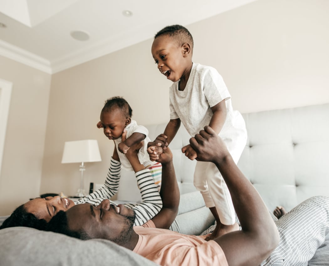 Happy family playing on the bed at Avilla Grace in Chandler, Arizona