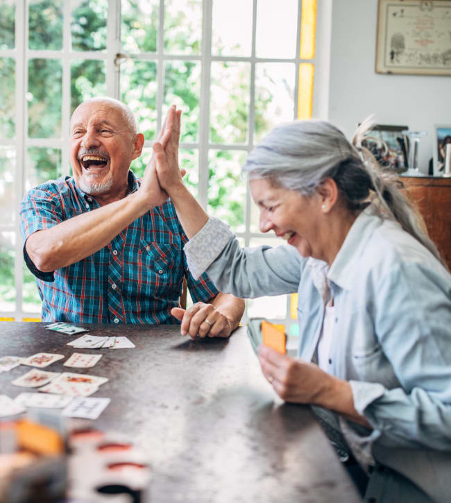 Two residents high fiving during a card game at Morris Glen in Alexandria, Virginia