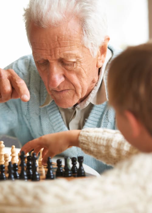 Young boy playing chess with his grandfather at Grand Villa of Delray West in Delray Beach, Florida