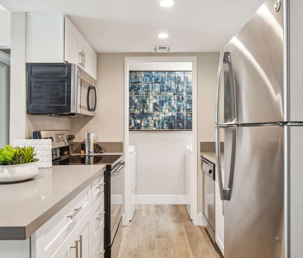 Modern kitchen with stainless-steel appliances and wood-style flooring at Sofi at Wood Ranch in Simi Valley, California