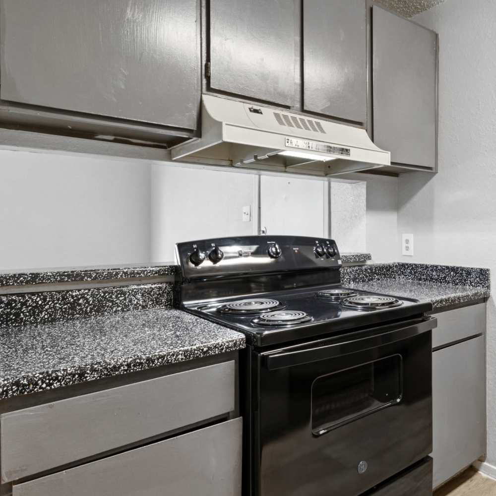 Black appliances and grey cabinets in the kitchen at Arbors of Taylor in Taylor, Texas