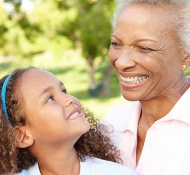 Resident and grandchild smiling outside at Carmel Village in Fountain Valley, California