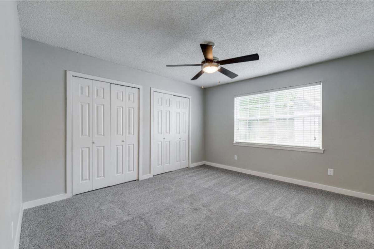 Spacious, charming bedroom with plush carpeting and natural light at Sangria Park in Austin, Texas.