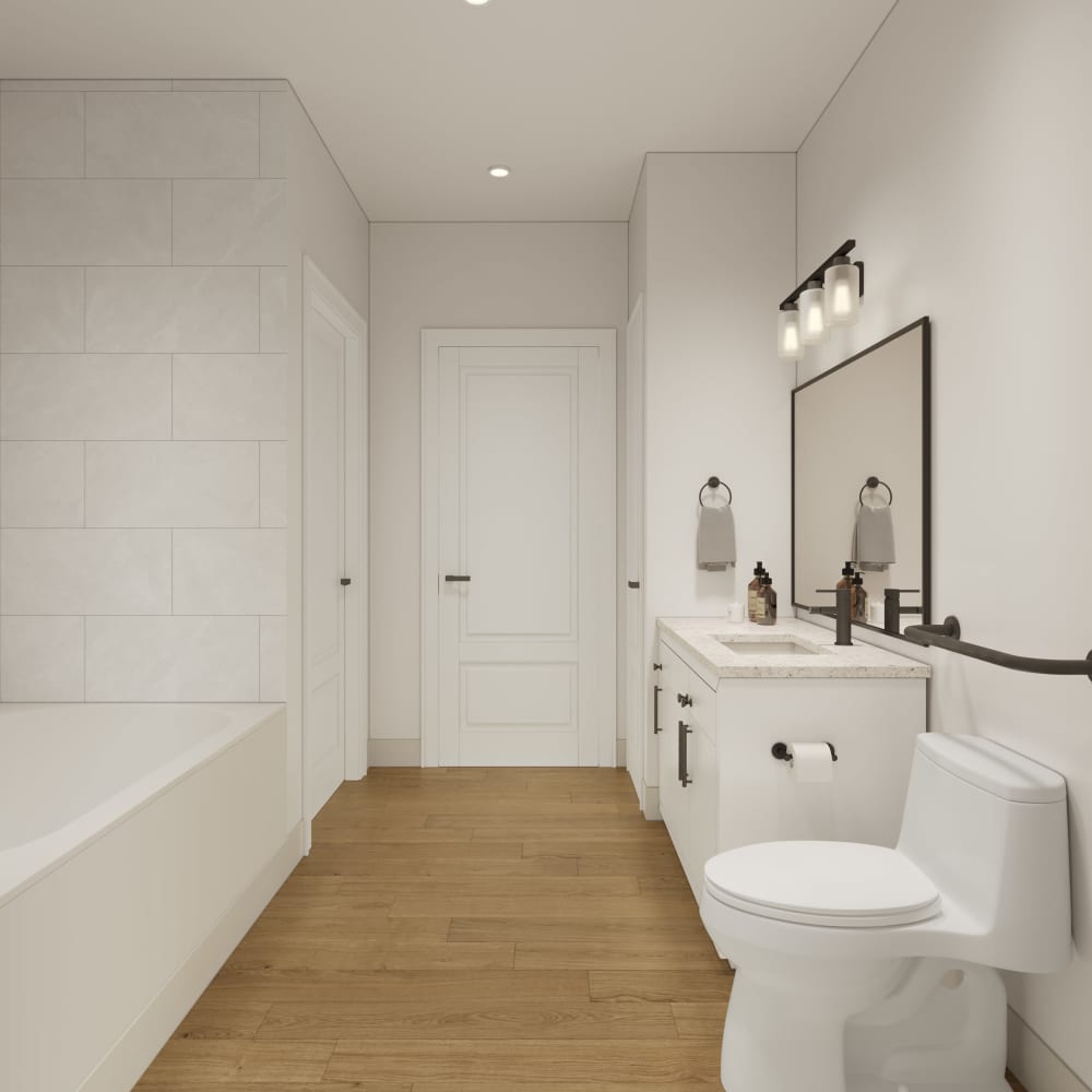 Bathroom with bathtub, tiled shower wall, vanity, mirror, and toilet at The Leo at Lewisville in Lewisville, Texas.