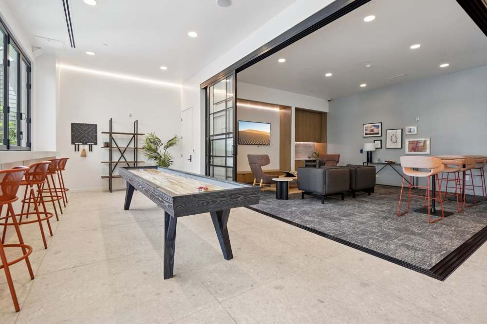 Modern lounge with shuffleboard table, seating, and decorative shelving at Tempo at Nine Mile Station in Aurora, Colorado