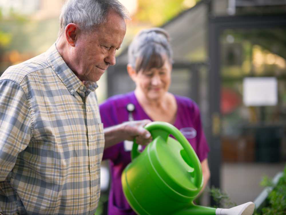 Resident watering plants with team member at Touchmark