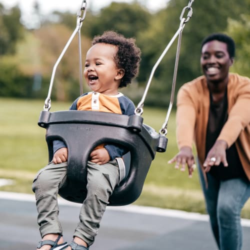 Resident pushing her child on a swing set at Franklin Commons, Bensalem, Pennsylvania