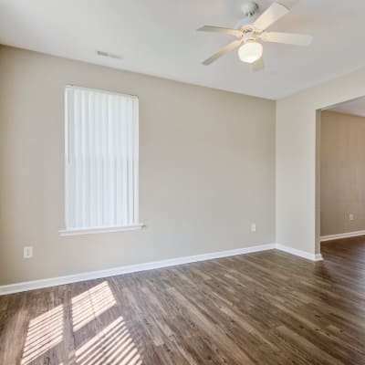 A  well-lit living room with wood flooring at The Village at Whitehurst Farm in Norfolk, Virginia