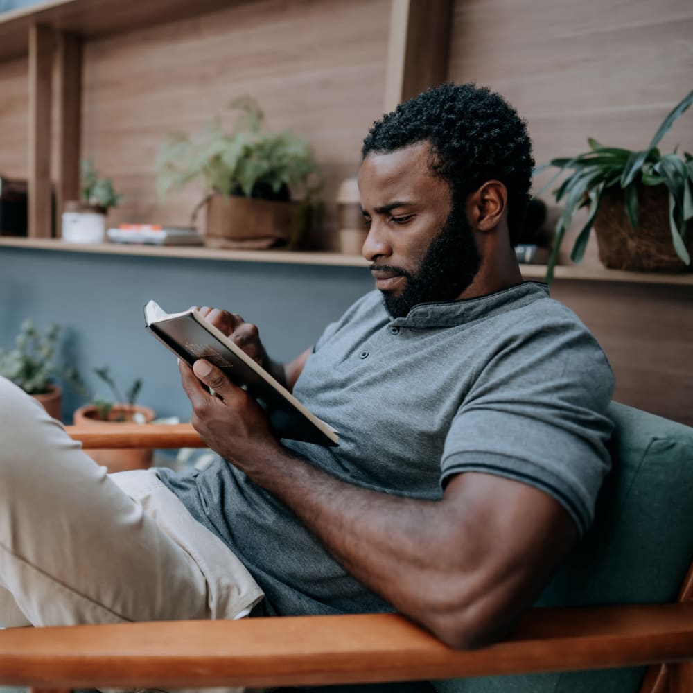 Resident reading a book on his couch at Brio Parc in Madison, Alabama