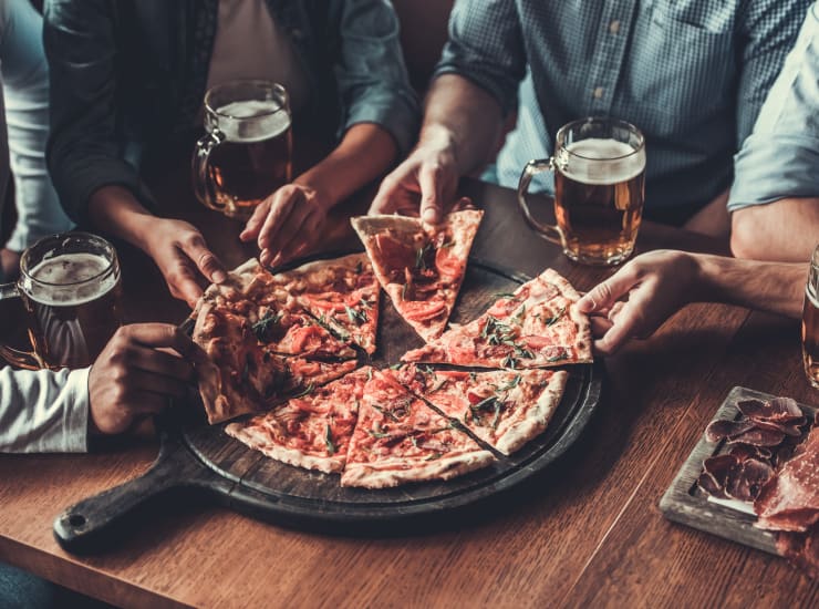 A group of friends sharing a pizza in a restaurant near Azalea Village in West Palm Beach, Florida