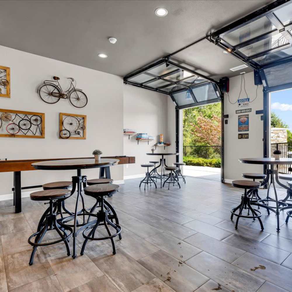 Bright community lounge with garage-style doors, modern seating, and bike-themed decor on the walls at 43 North Apartments in Grand Haven, Michigan