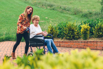 Resident being taken on a walk in her wheelchair at Mirror Lake Village Senior Living Community in Federal Way, Washington.