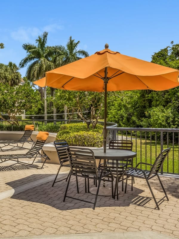 Sundeck patio tables with umbrellas at Tuscany Pointe at Somerset Place Apartment Homes in Boca Raton, Florida