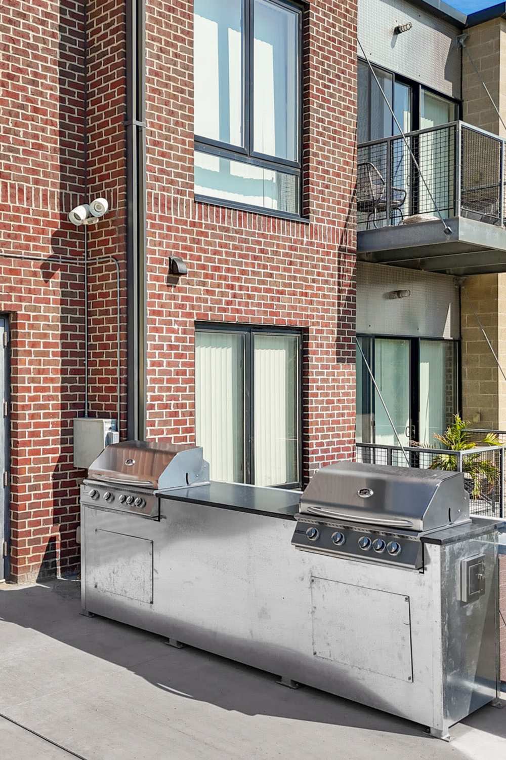 Outdoor grilling station with stainless steel grills near modern brick apartment building at Ingersoll Square in Des Moines, Iowa