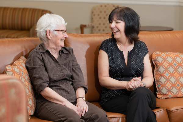 Resident and team member sitting on a couch.