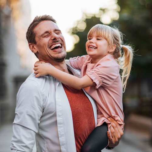 Adult holding child outdoors in soft evening light at Regents Park Apartments in Bensenville, Illinois