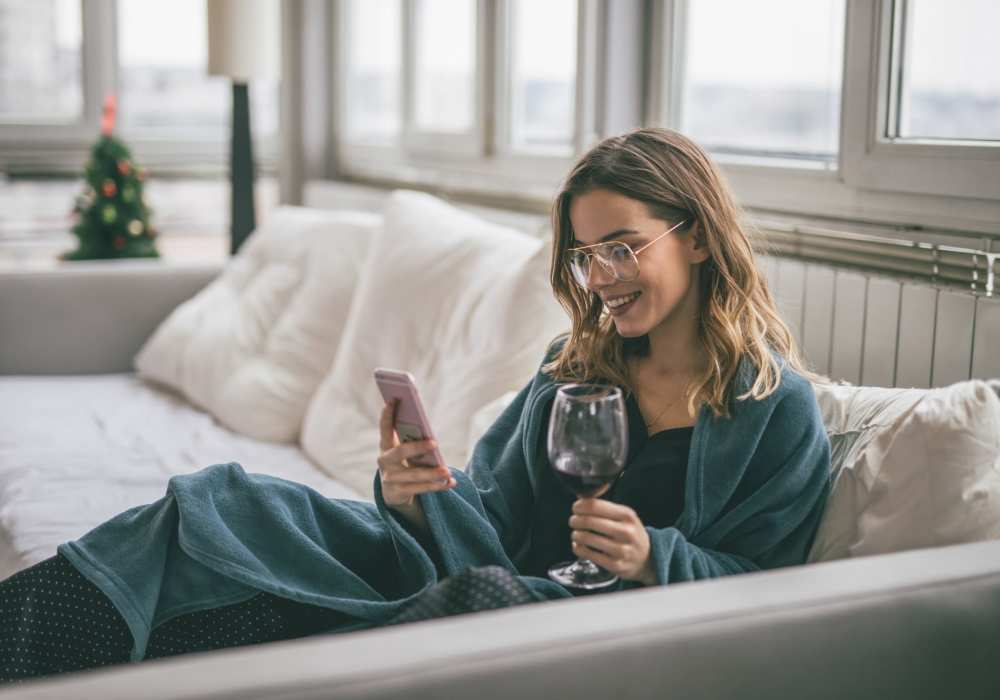 Woman enjoying a drink and checking her phone in the comfortable living room at Village on Mercy in Orlando, Florida