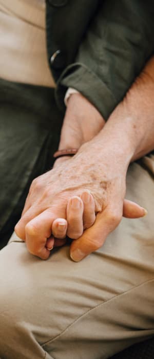 Two residents holding hands and sitting side-by-side at a WISH community