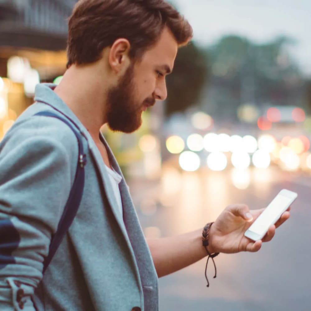 Resident waiting for public transit while surfing the web on his smartphone near Oaks Station Place in Minneapolis, Minnesota