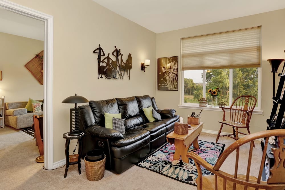 Sitting room with black leather sofa in apartment at Hillcrest of Loveland in Loveland, Colorado