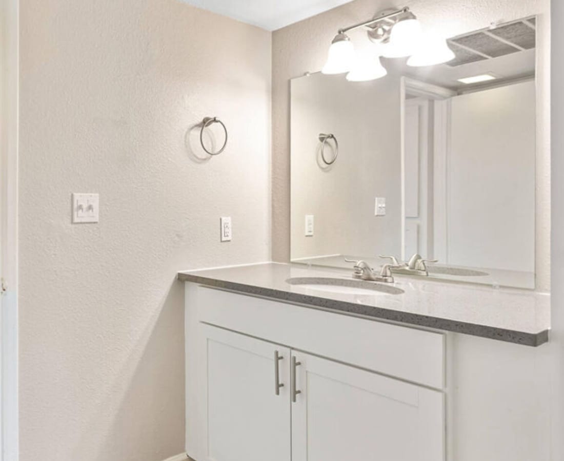 Bright bathroom with a big mirror and storage space at Raystone Apartments in Phoenix, Arizona