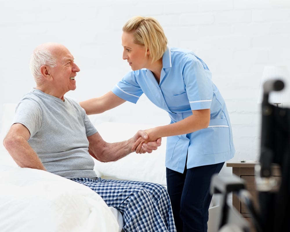 Staff assisting resident out of bed at Milestone Senior Living Faribault in Faribault, Minnesota.